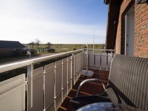 balcón con banco y vistas a un campo en Seaside 26, en Friedrichskoog