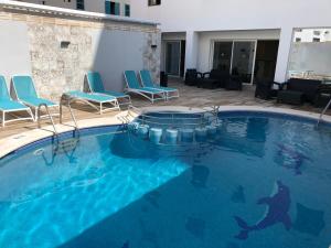 a large swimming pool with blue chairs and a swimming pool at Hostal Rosalia in San Antonio