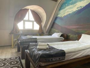 a room with three beds with a painting on the wall at Eco House in Osh
