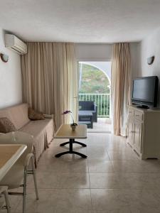 een woonkamer met een bank en een tv bij Apartamentos Torres Cardona (Playa) in Cala Llonga