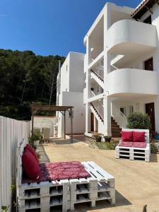 łóżko przed białym budynkiem z różowymi poduszkami w obiekcie Apartamentos Torres Cardona (Playa) w mieście Cala Llonga