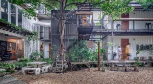 ein Gebäude mit einem Baum mit einer Leiter und Bänken in der Unterkunft The Yard Bangkok Hostel in Bangkok