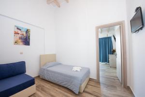 a bedroom with a bed and a couch and a mirror at Angela Beach Hotel & Apts in Roda