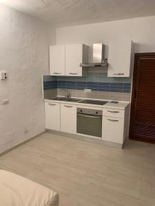 a kitchen with white cabinets and a stove top oven at Appartamento in Costa Smeralda - Bilocale sul mare - Sea View in Olbia