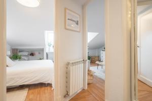 a white bedroom with a bed and a hallway at Txori-Toki in Zarautz