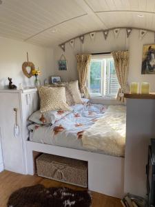 Cama grande en habitación con ventana en Willowbank shepherds hut, en Taunton