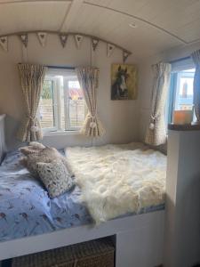 Willowbank shepherds hut في تونتون: سرير في غرفة صغيرة بها نافذتين