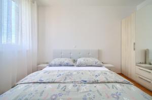 a white bedroom with a large bed with blue pillows at Apartment Anja in Krk