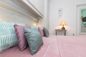 Un dormitorio con una cama rosa con almohadas moradas y azules en Room Gržetić en Šilo