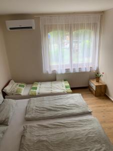 Dos camas en una habitación con ventana. en Zsuzsa Apartman Hajdúszoboszló, en Hajdúszoboszló