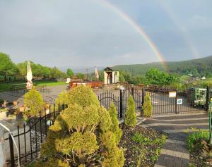 a rainbow over a garden with a park with a playground at Agal Zieleniec in Zieleniec