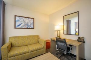 a hotel room with a couch and a desk and a chair at Wingate by Wyndham Brunswick GA I-95 in Brunswick