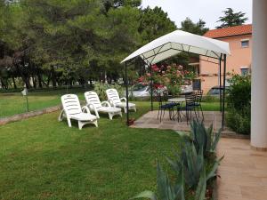 een groep stoelen en tafels onder een witte paraplu bij Apartment Frleta in Umag