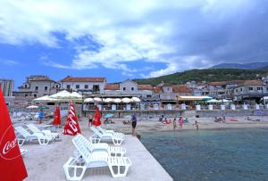 a beach with a bunch of chairs and people on it at Tamaris Apartmani in Herceg-Novi