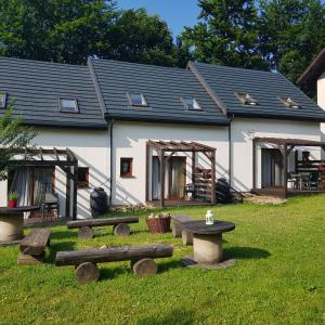 a house with benches in the grass in front of it at Osada nad Potokiem in Szczyrk