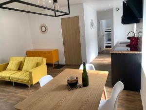 ein Wohnzimmer mit einem Tisch und einem gelben Sofa in der Unterkunft Appartement calme et chaleureux in Concarneau