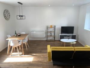 ein Wohnzimmer mit einem gelben Sofa und einem Tisch in der Unterkunft Appartement calme et chaleureux in Concarneau