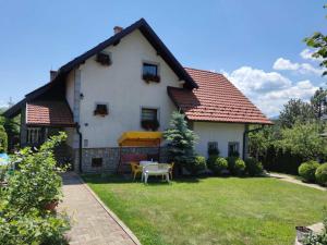 uma casa branca com um quintal com uma mesa em Privatni Smeštaj Tešević em Zlatibor