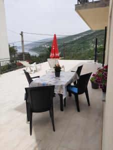 stół z krzesłami i czerwony parasol na patio w obiekcie Apartments Roby w mieście Sveti Juraj
