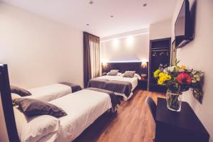 a hotel room with two beds and a table with flowers at Hostal Marlasca in Madrid