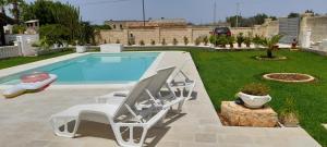 een zwembad met 2 ligstoelen en een zwembad bij B&B Cinque Stelle Salento in Marina di Mancaversa