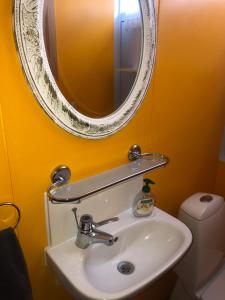 a bathroom with a sink and a mirror on a yellow wall at Guesthouse Langafit in Laugarbakki