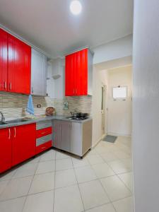 a kitchen with red cabinets and a white tile floor at Beach Apartaments in Durrës