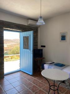 Habitación con puerta azul, mesa y cama en Villa Aphrodite en Koundouros