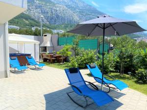 a group of chairs and an umbrella on a patio at Lux Apartment Školjka in Makarska