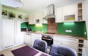 una cocina con armarios blancos y una pared verde en Nice Home In Techelsberg With 1 Bedrooms And Wifi, en Techelsberg am Worthersee