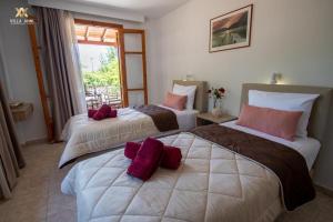 two beds in a hotel room with purple pillows at Villa Anni in Skiathos Town