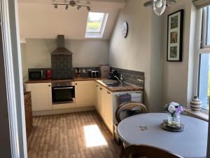 a kitchen with a table and a sink and a stove at Ty'n y Gwynt in Criccieth