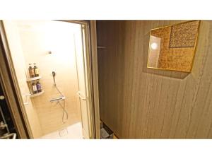 uma casa de banho com um chuveiro e uma porta de vidro em Petit Hotel mio em Saitama