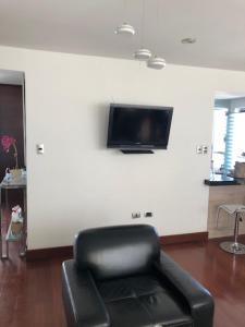 a living room with a chair and a tv on a wall at challapampa apart's in Arequipa