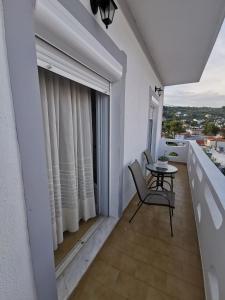a balcony with a table and chairs and a window at Bralos Apartments in Patitiri