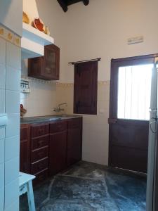 a kitchen with wooden cabinets and a door with a window at Casa da Avó Velhinha in Telheiro