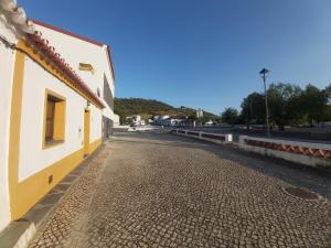 una calle adoquinada junto a un edificio blanco y amarillo en Casa da Avó Velhinha, en Telheiro