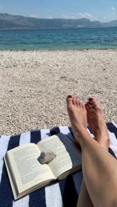 uma pessoa deitada numa toalha com um livro na praia em Family house KAŠTELA HOME between Split and Trogir em Kaštela