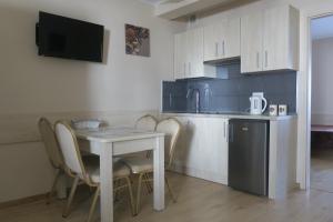 a kitchen with a table and chairs and a small table with a tablektop at Apartament Angelit in Rowy
