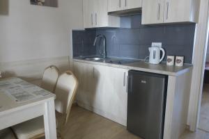 a small kitchen with white cabinets and a sink at Apartament Angelit in Rowy +10 photos