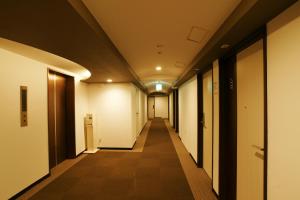 un largo corredor con paredes blancas y un largo pasillo con una estampa en Hotel Century Art en Fukuoka
