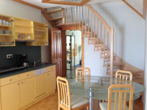 une cuisine avec une table en verre et un escalier en colimaçon dans l'établissement Haus Rose, à Wenigzell
