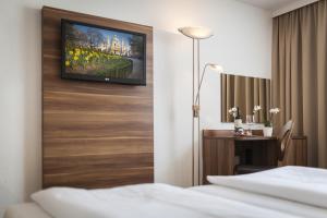 a bedroom with a television and a bed at Hotel Enziana Wien in Vienna