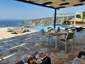eine Terrasse mit einem Tisch, Stühlen und einem Pool in der Unterkunft Villa Esperia in Kampíon
