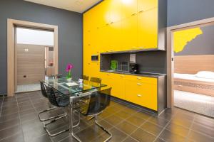 cocina con mesa de cristal y armarios amarillos en E14 Design Hostel, en Budapest