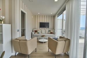 un salon avec un canapé et deux chaises dans l'établissement Malibú Canteras Ático 23 Vista Mar - Seaview Penthouse, à Las Palmas de Gran Canaria