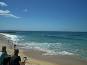 dos personas sentadas en la playa mirando el océano en Vina's Beach House - 2 minute walk to the beach, en Costa da Caparica