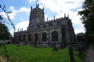 an old church with a tower on a grass field at The Nurseries Bed and Breakfast Fairford in Fairford