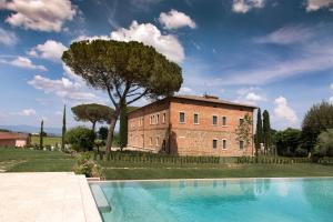 un grand bâtiment en briques avec un arbre et une piscine dans l'établissement Villa Svetoni Wine Resort, à Montepulciano