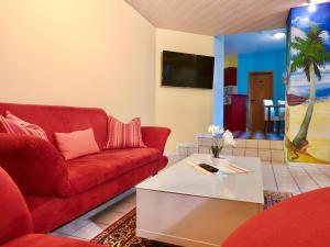 Sala de estar con sofá rojo y mesa de centro en Ferienwohnung Gartenblick, en Remchingen